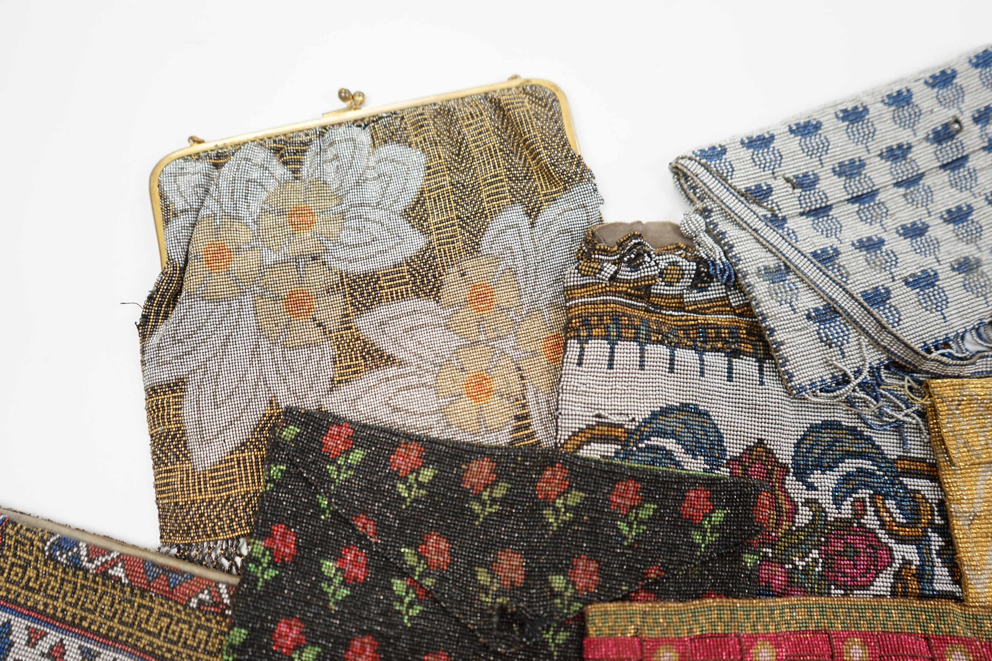 Seven late 19th century multicoloured and designed cut steel evening bags and a small coin purse (8)